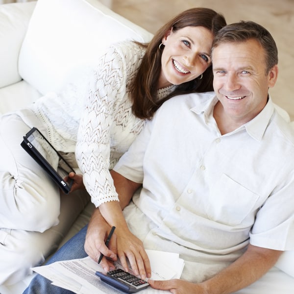 Smiling relaxed middle-age couple using tablet and pocket computer at home